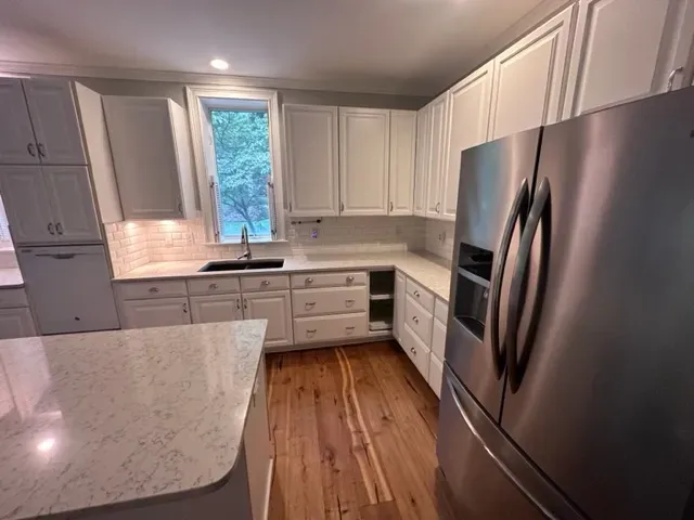 A kitchen with white cabinets and a stainless steel refrigerator