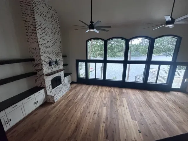A living room with hardwood floors , a fireplace and a ceiling fan.
