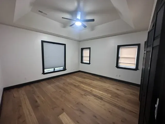 An empty bedroom with hardwood floors and a ceiling fan.