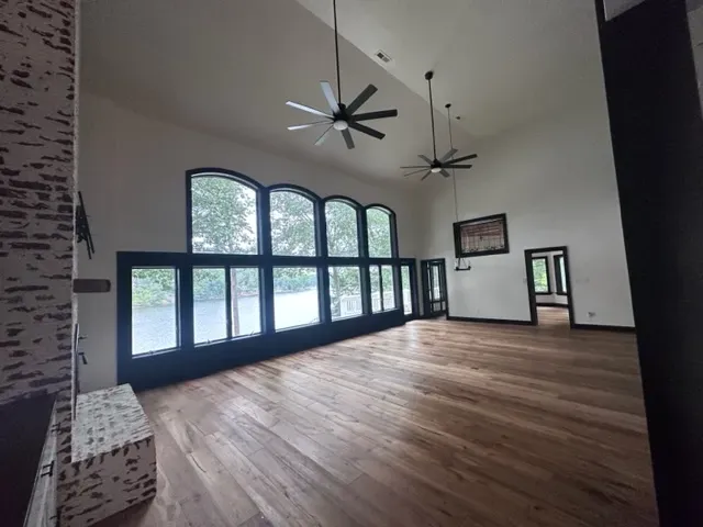 An empty room with arched windows and a ceiling fan