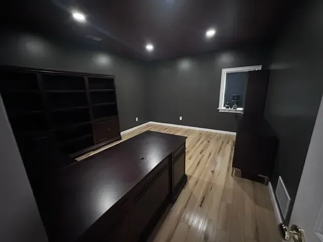A dark room with a desk and shelves in it