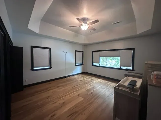 An empty room with hardwood floors and a ceiling fan