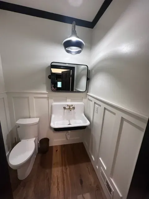 A bathroom with a toilet a sink and a mirror