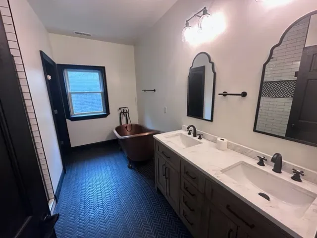 A bathroom with two sinks , a tub and two mirrors.