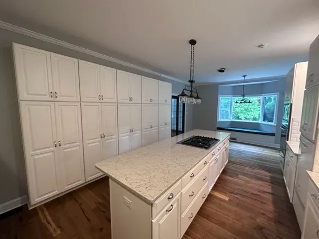 A kitchen with white cabinets and a large island in the middle.