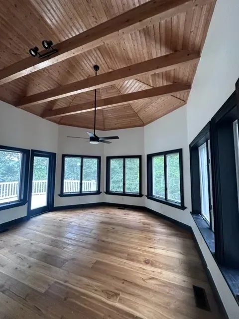 An empty room with a ceiling fan and lots of windows