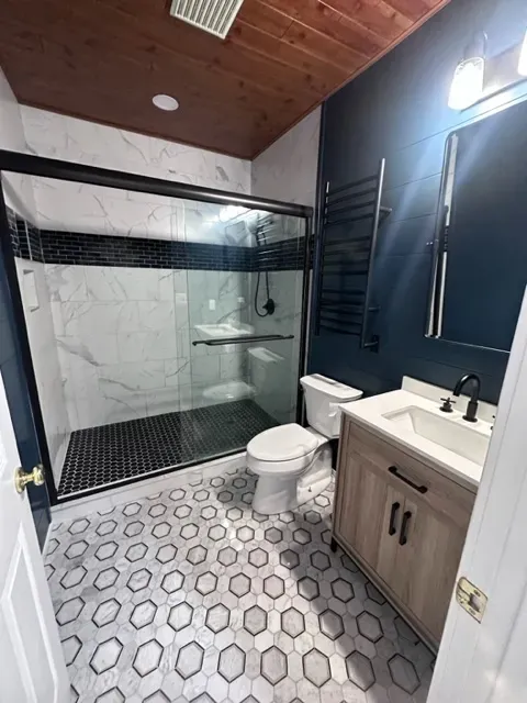 A bathroom with a toilet , sink , shower and mirror.
