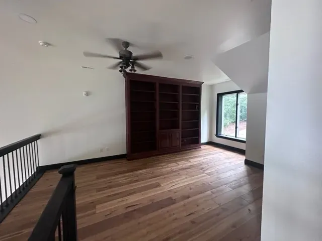 An empty room with hardwood floors and a ceiling fan