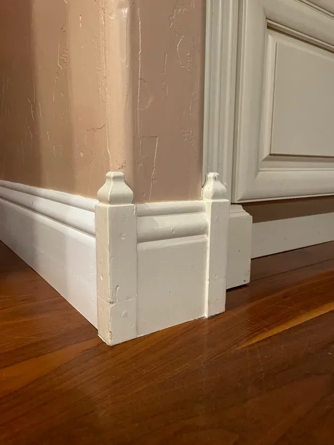 A close up of a white molding on a wooden floor.