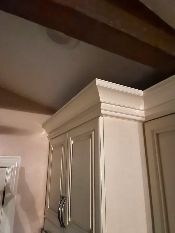 A kitchen with white cabinets and wooden beams