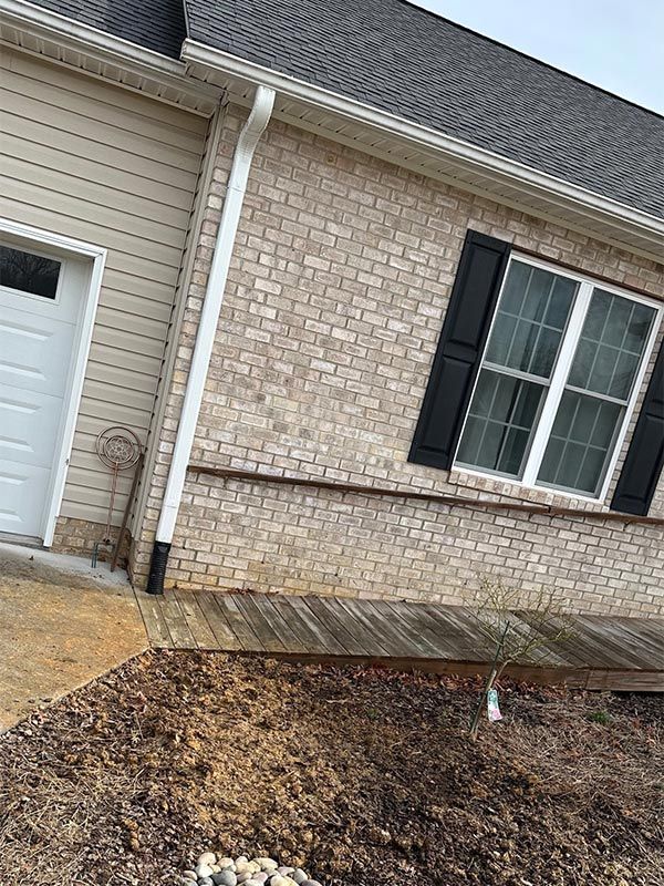 A brick house with a white garage door and black shutters.