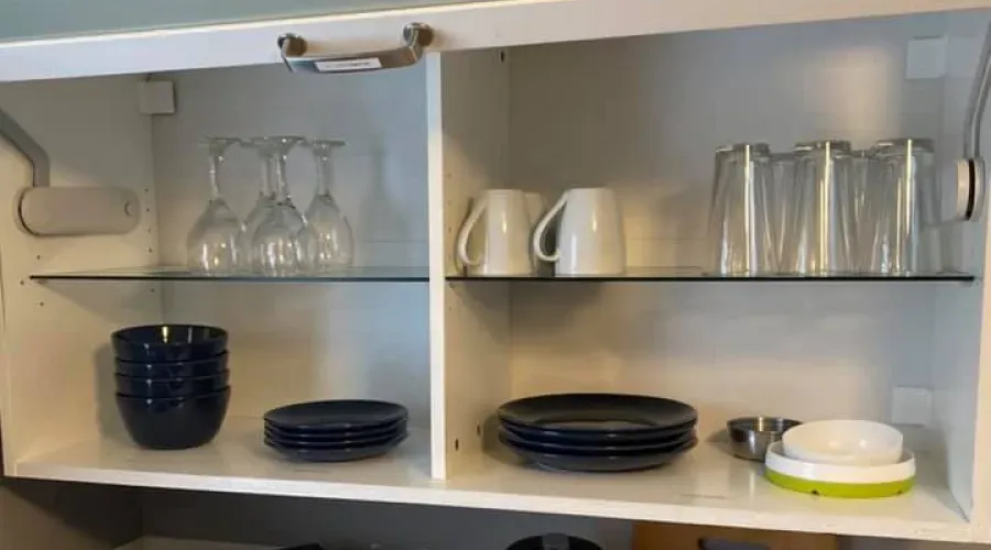 A kitchen cabinet filled with plates , cups , and glasses.