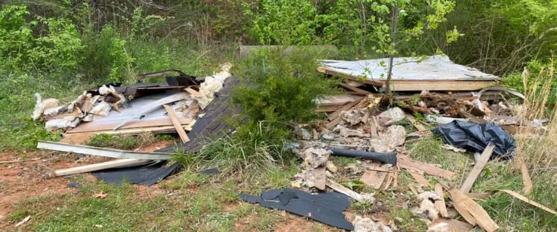 A pile of wood is laying on the ground in a field.