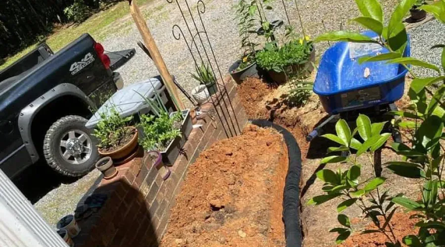 A black truck is parked next to a blue wheelbarrow filled with dirt.