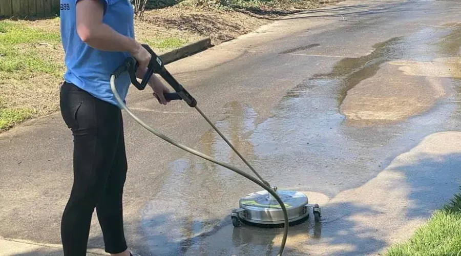 A woman is using a pressure washer to clean a driveway.