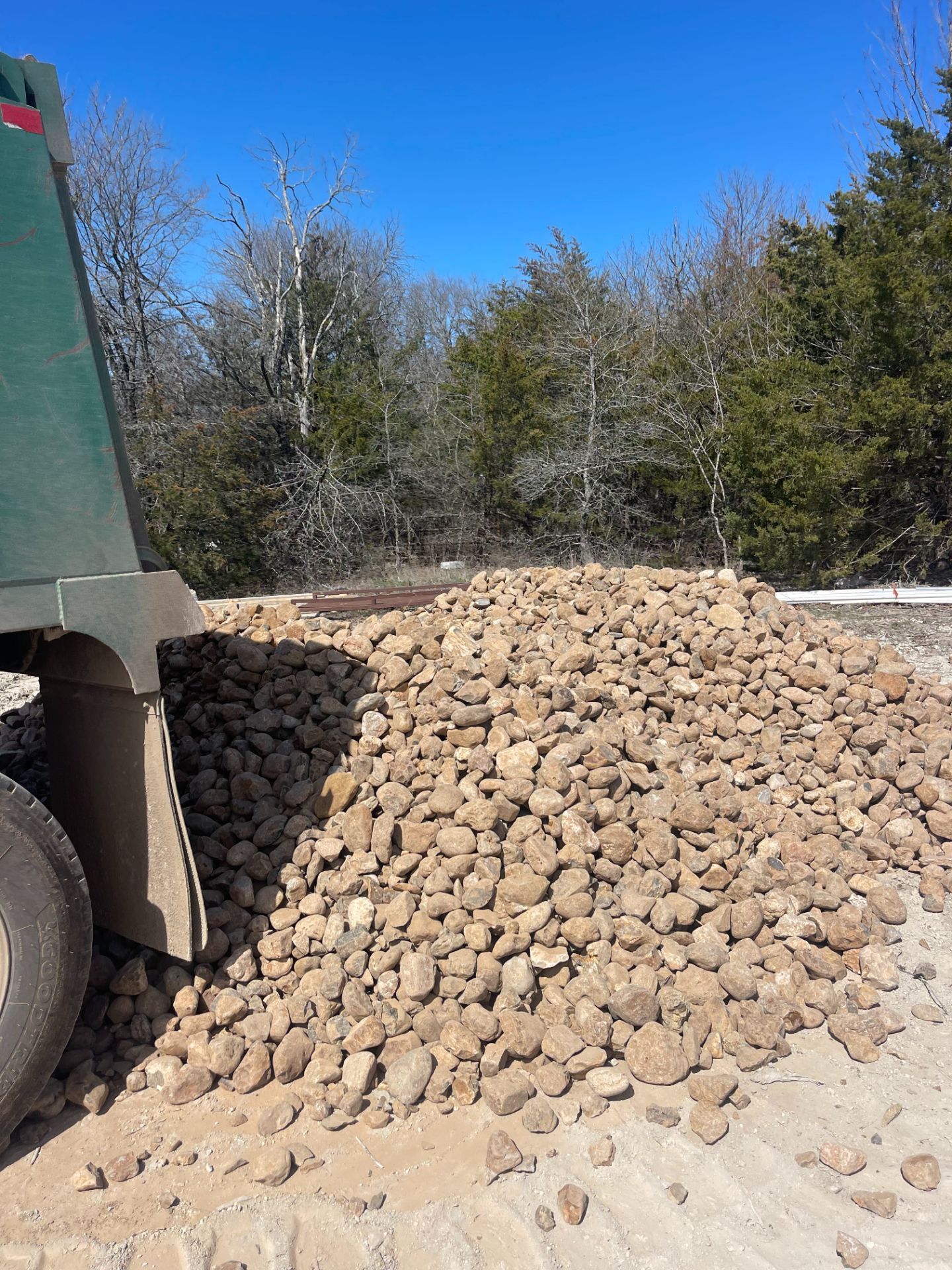 A dump truck is carrying a pile of rocks on a dirt road.