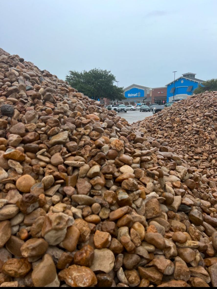 A pile of rocks is sitting in front of a walmart store.