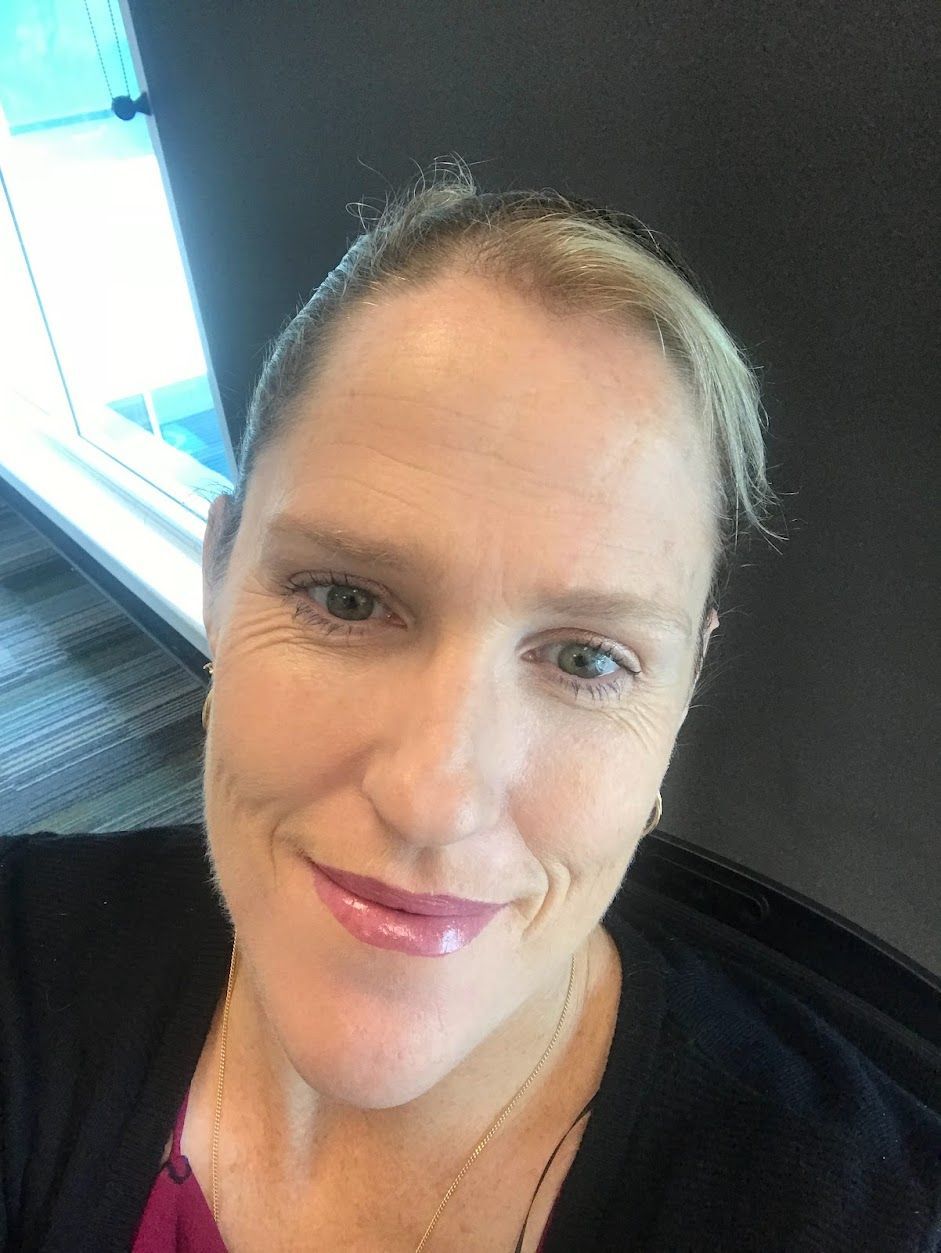 Woman Smiling, Holding Keys, Sitting at a Desk With Laptop and Papers — Wingman Conveyancing in Woodroffe, NT