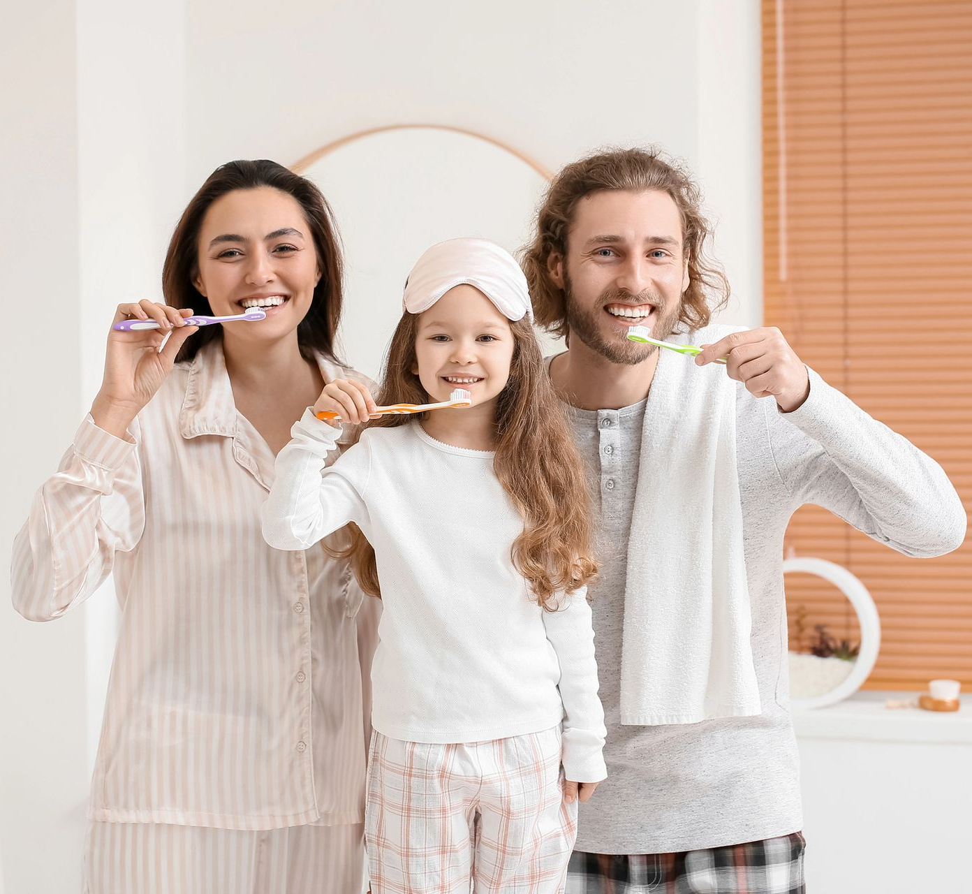 Family brushing their teeth in bathroom.
