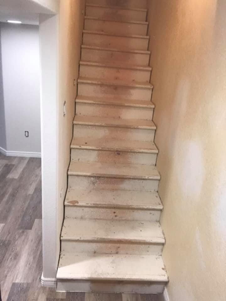 a staircase in a basement with wooden steps and a wooden floor .
