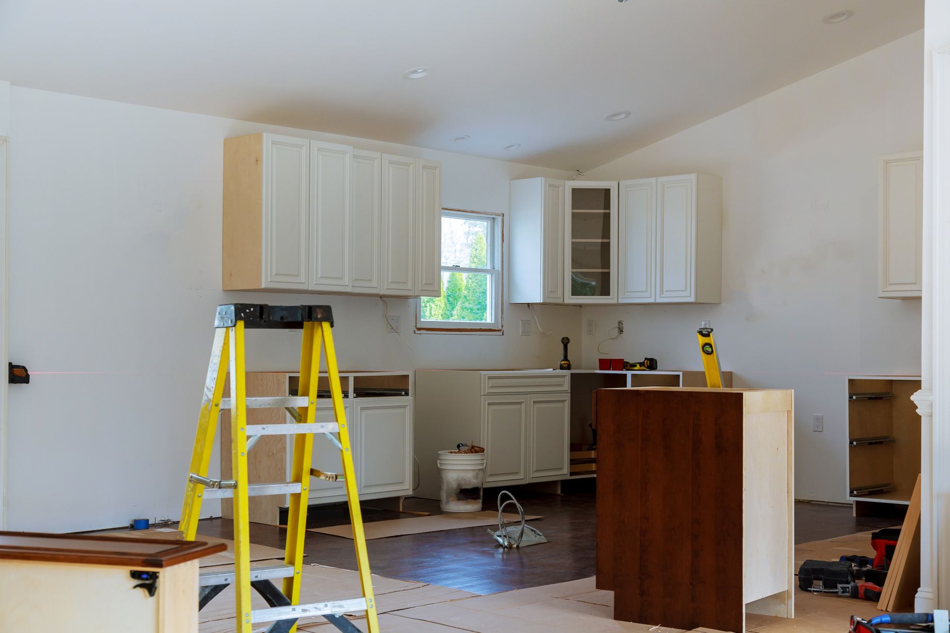 a kitchen is being remodeled with white cabinets and a yellow ladder