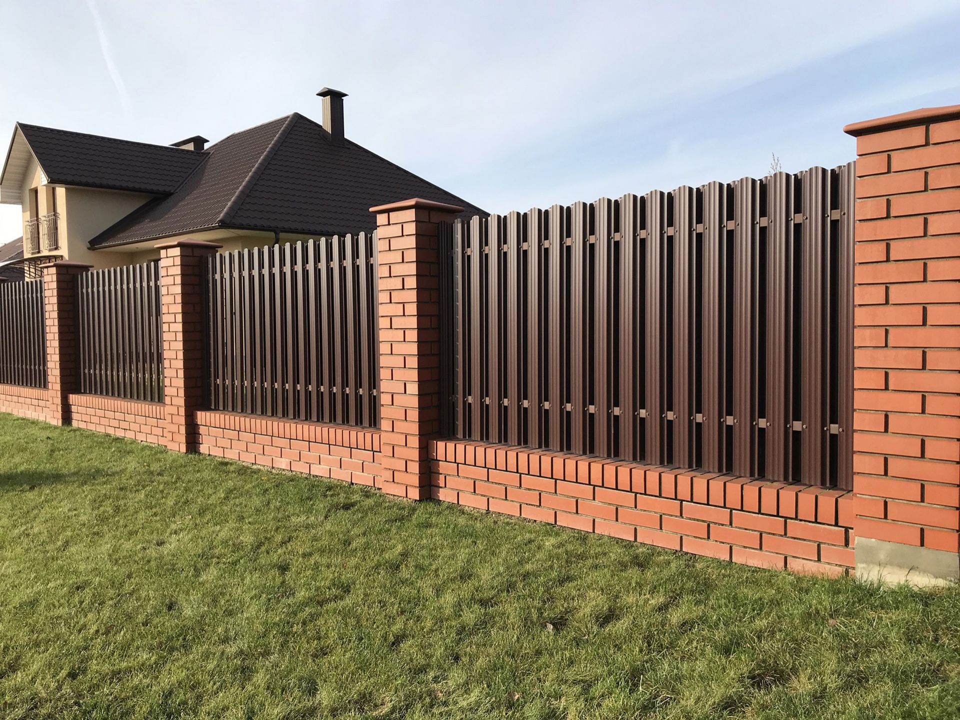 a brick fence with a metal fence in front of a house