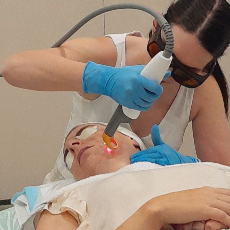 A woman is using a laser on a patient 's face