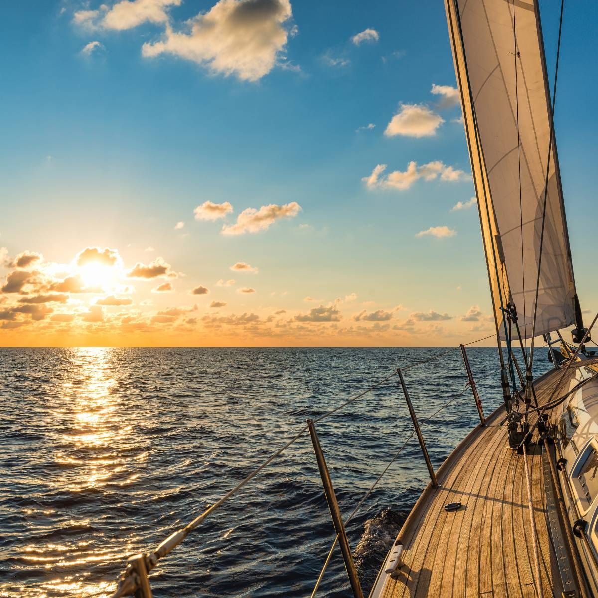 A sailboat is sailing in the ocean at sunset