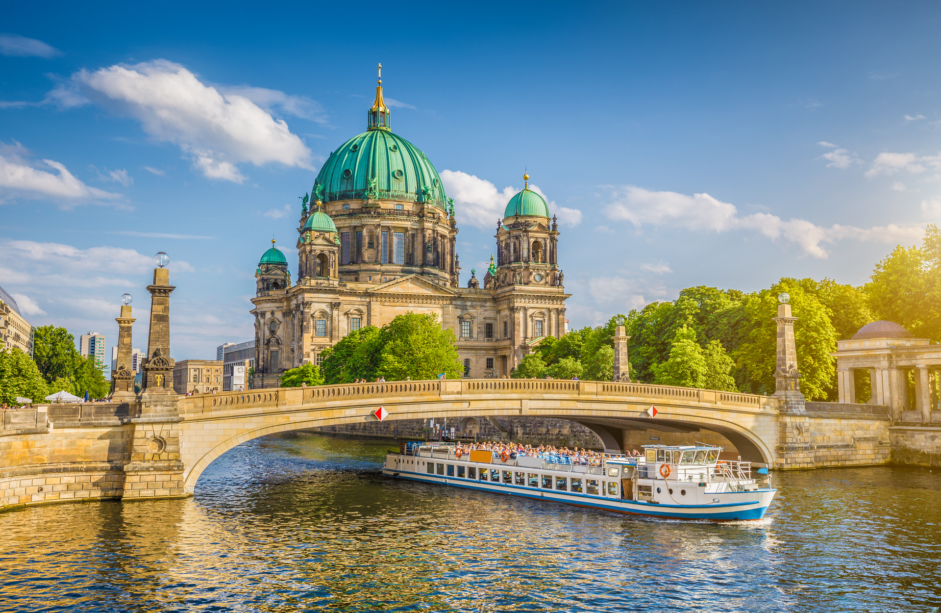 A boat is going under a bridge in front of a large building.