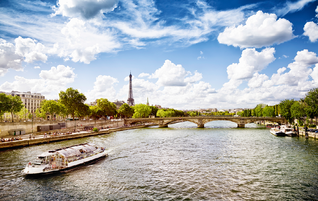 A boat is floating on a river in paris with the eiffel tower in the background.