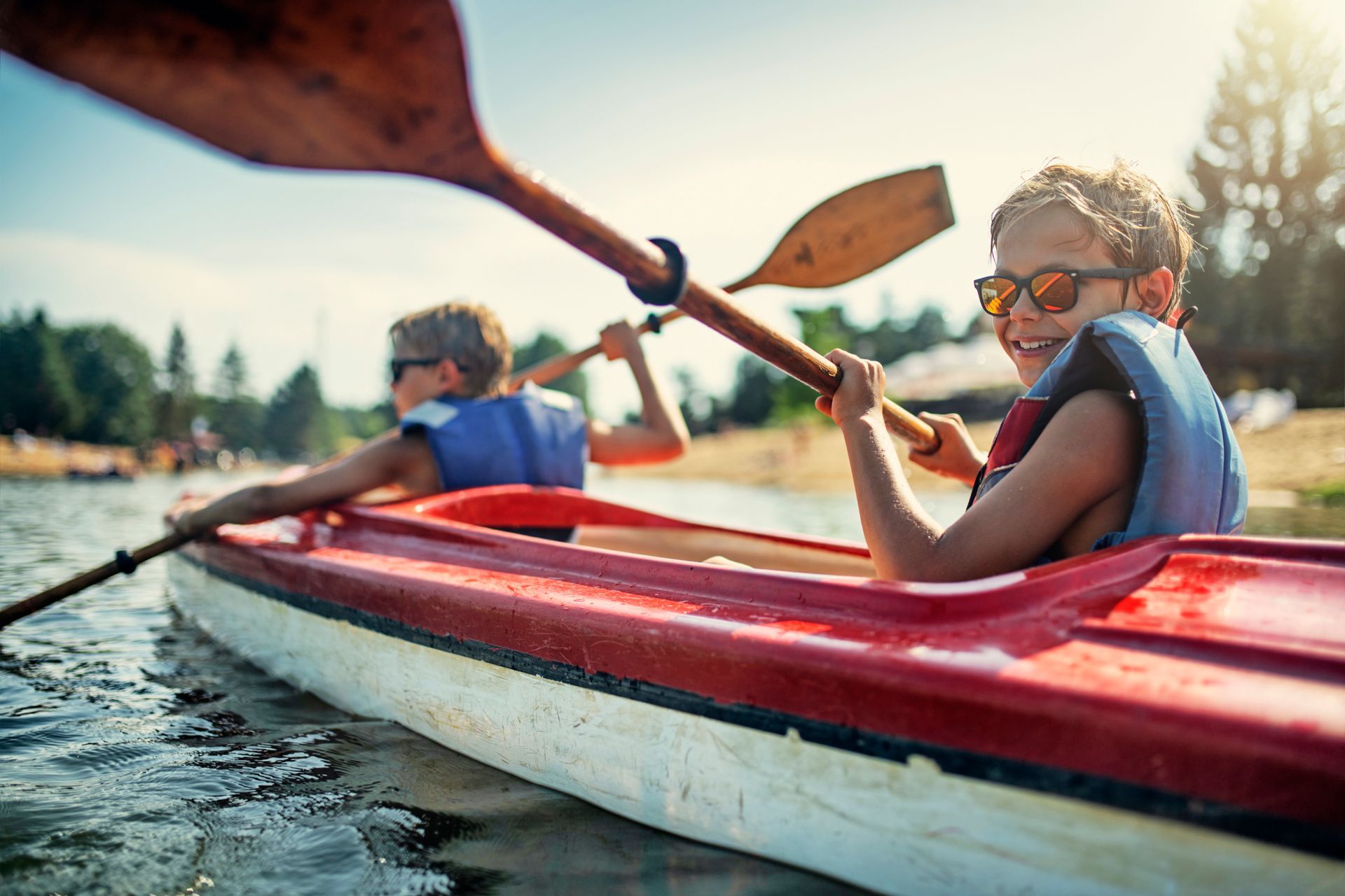 A boy and a girl are paddling a kayak on a lake.