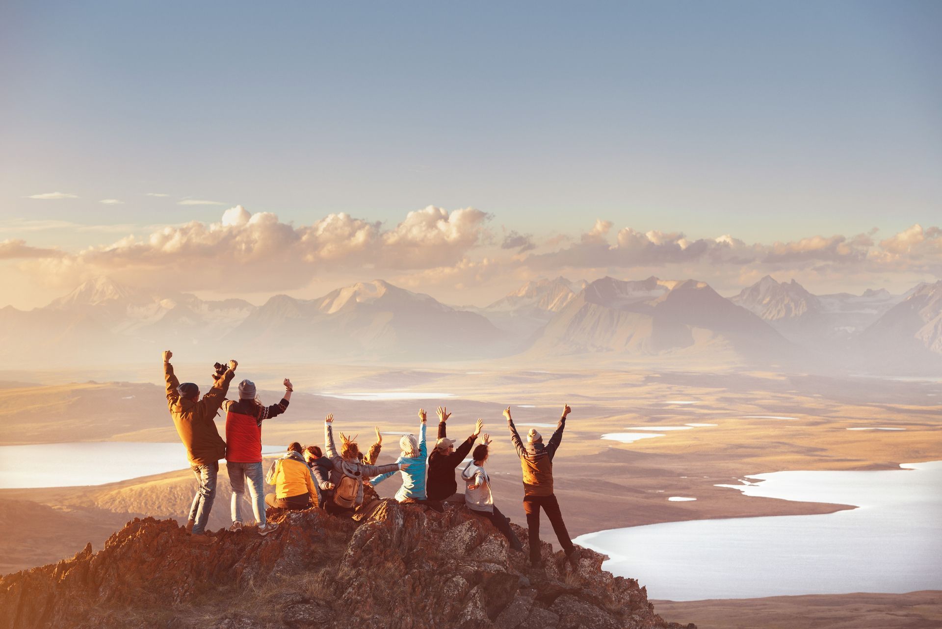 A group of people are standing on top of a mountain with their arms in the air.