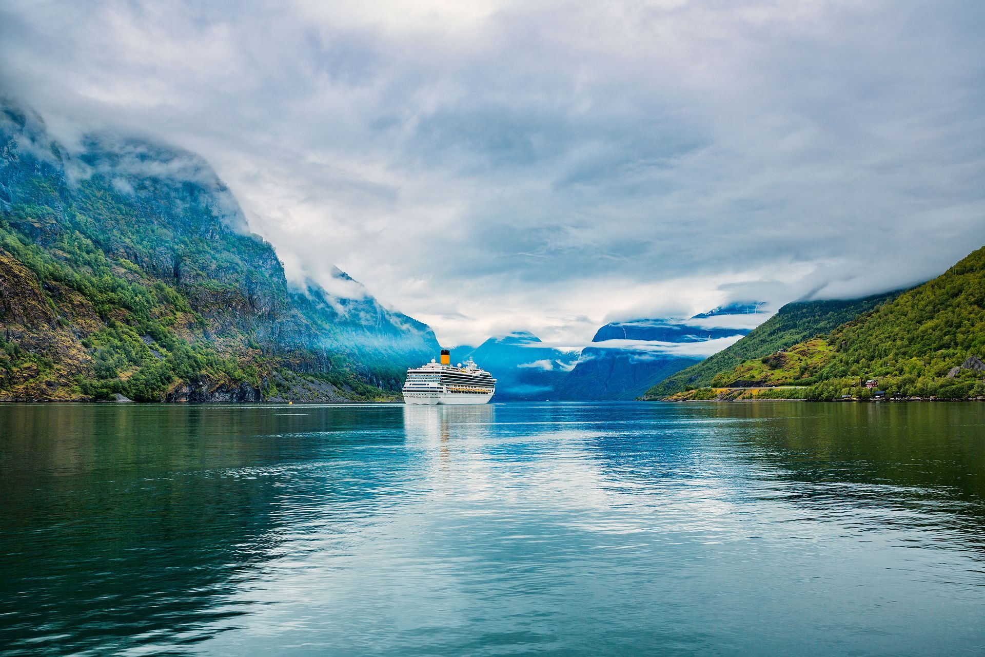 A cruise ship is floating on top of a lake surrounded by mountains.