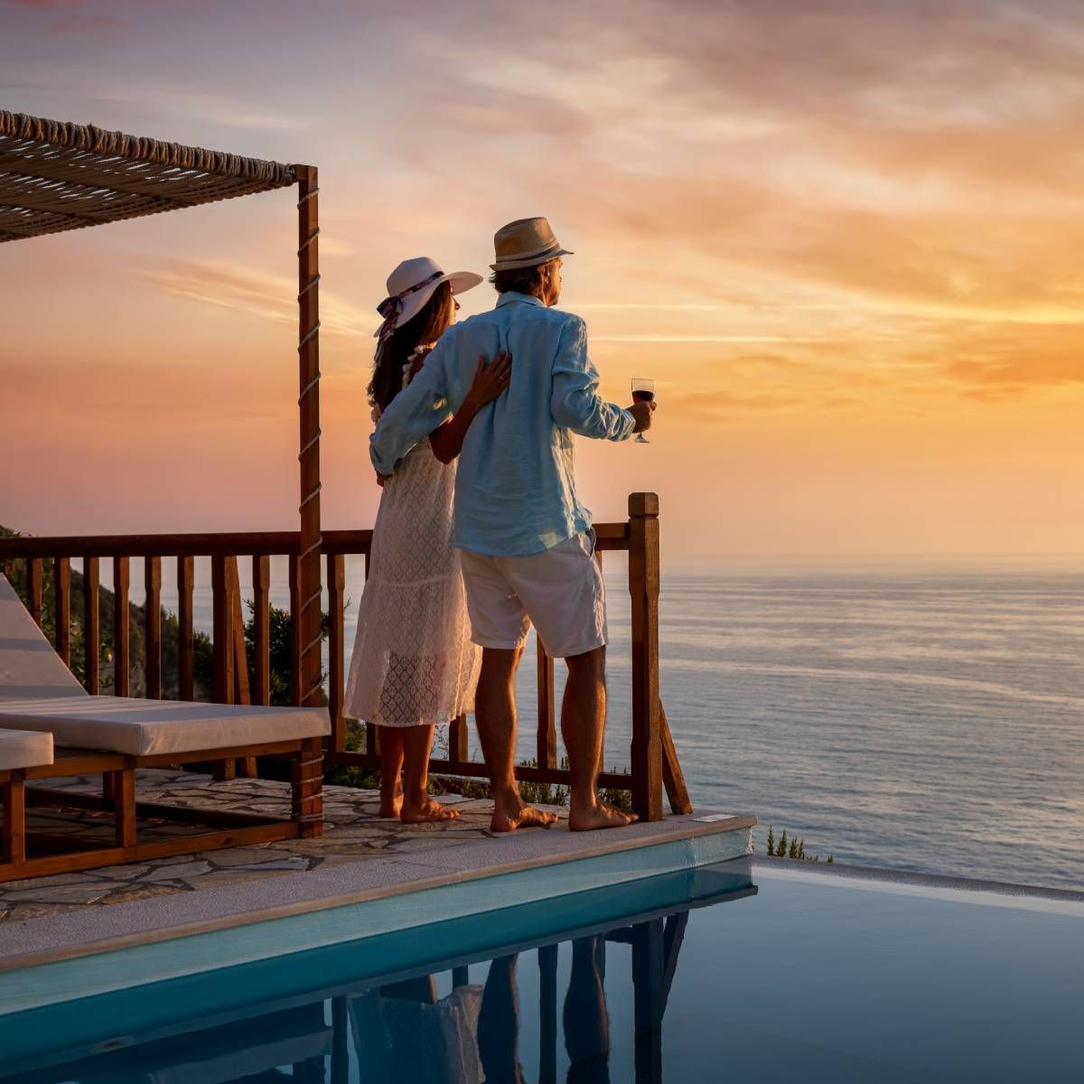 A man and woman are standing on a balcony overlooking the ocean