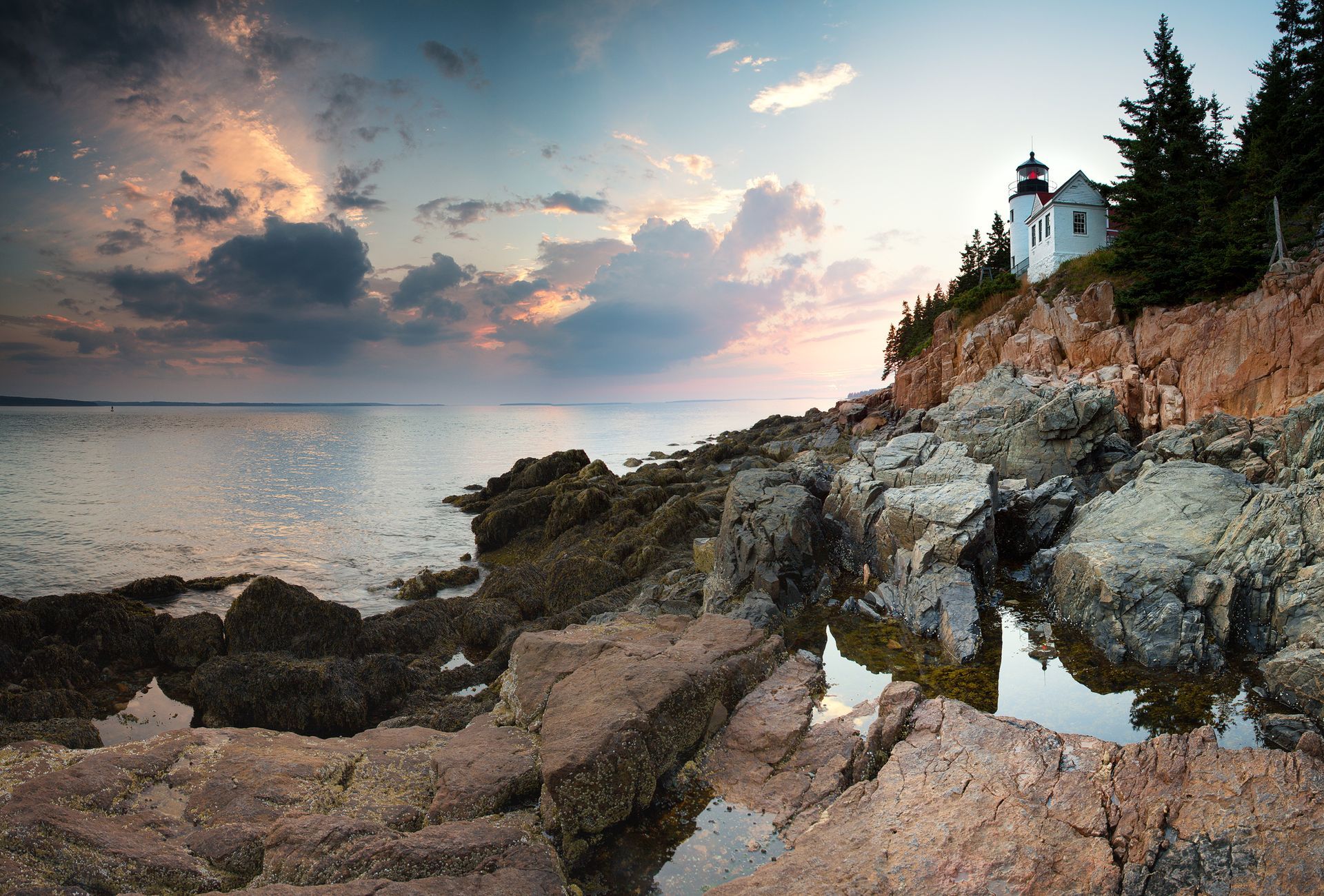 A lighthouse is sitting on top of a rocky cliff overlooking the ocean.