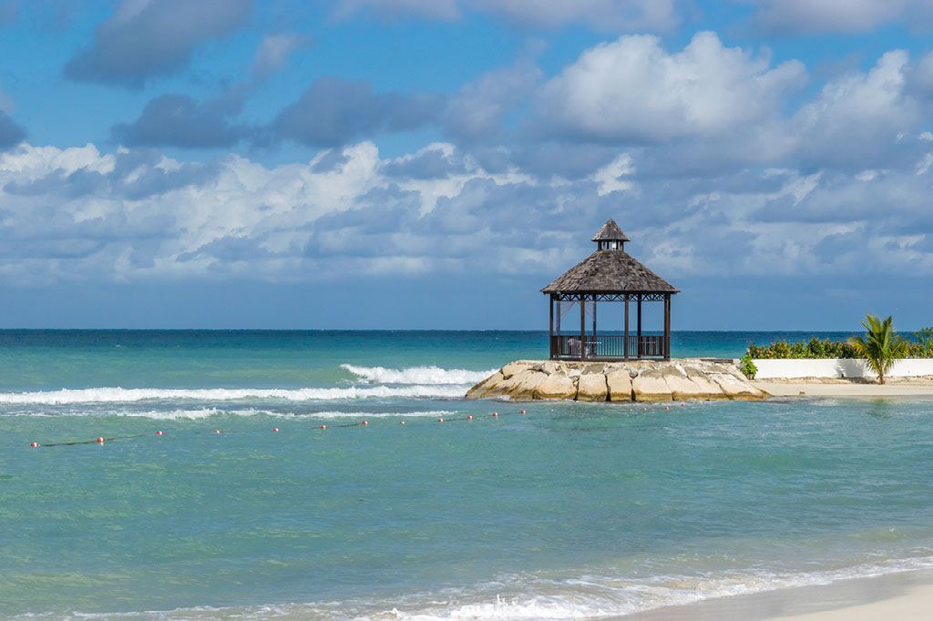 A gazebo on a small island in the middle of the ocean.