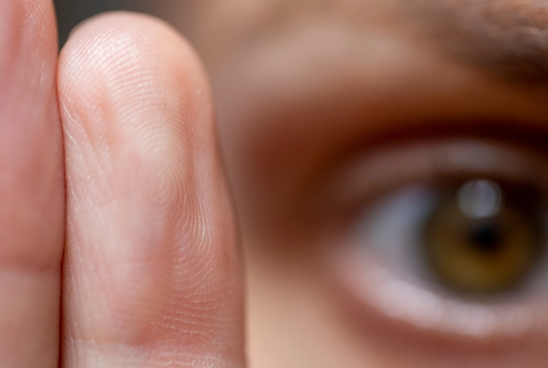 A close up of a person 's finger covering their eye.