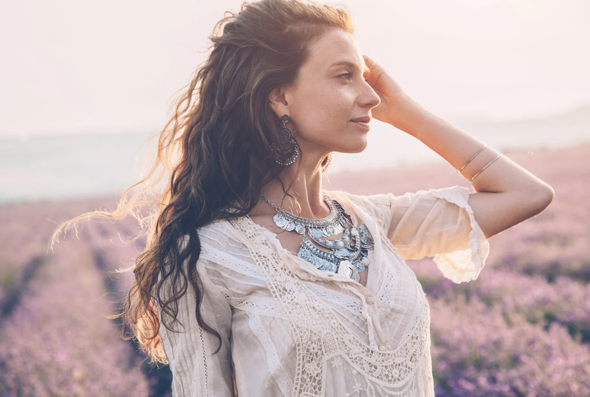 A woman in a white dress is standing in a field of purple flowers.