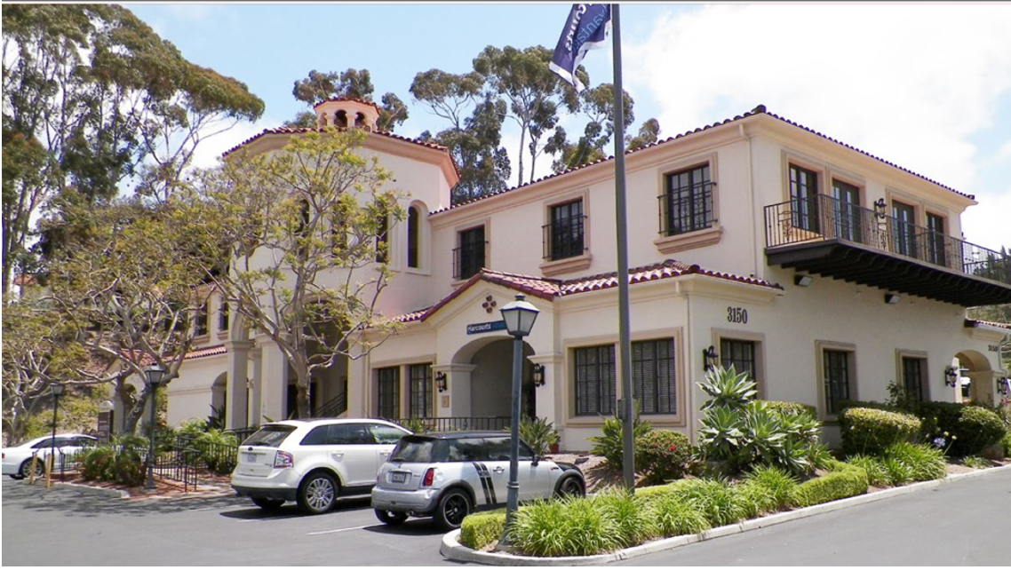 A large white building with cars parked in front of it