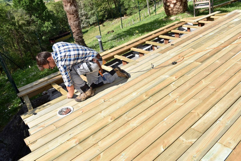 Worker Installing Wooden Decking on An Outdoor Roof Frame with Tools Nearby — WJG Built in Byron Bay, NSW