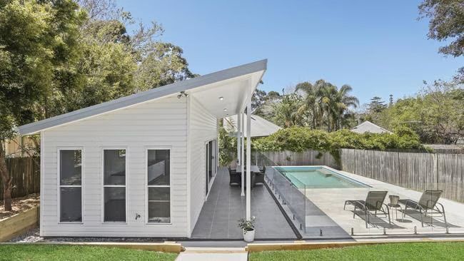 White house beside a pool with a deck and lounge chairs in a sunny backyard — WJG Built in Wollongbar, NSW