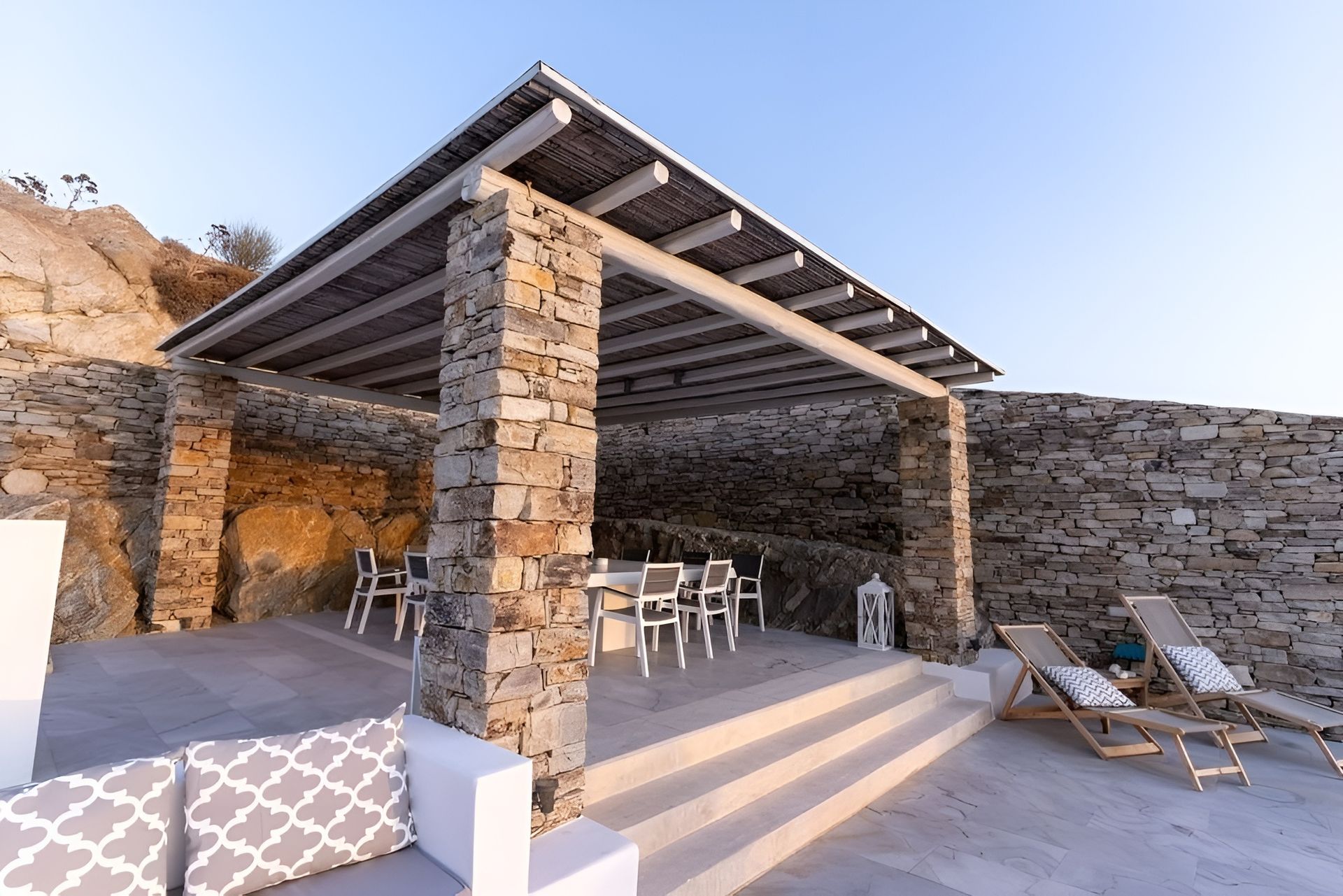 Stone-Patio Outdoor Lounge with A Shaded Pergola and Sun Loungers by A Rocky Hillside — WJG Built in Wollongbar, NSW
