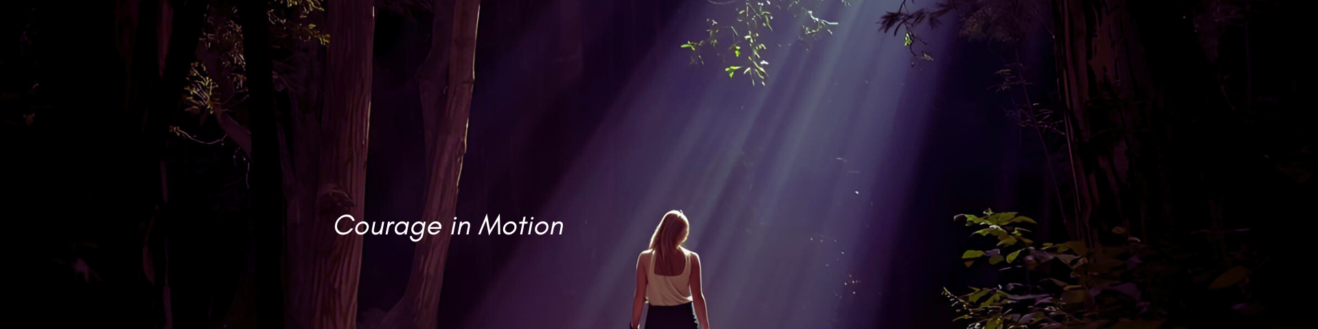 Woman with her back to us standing in beam of light on a forest path