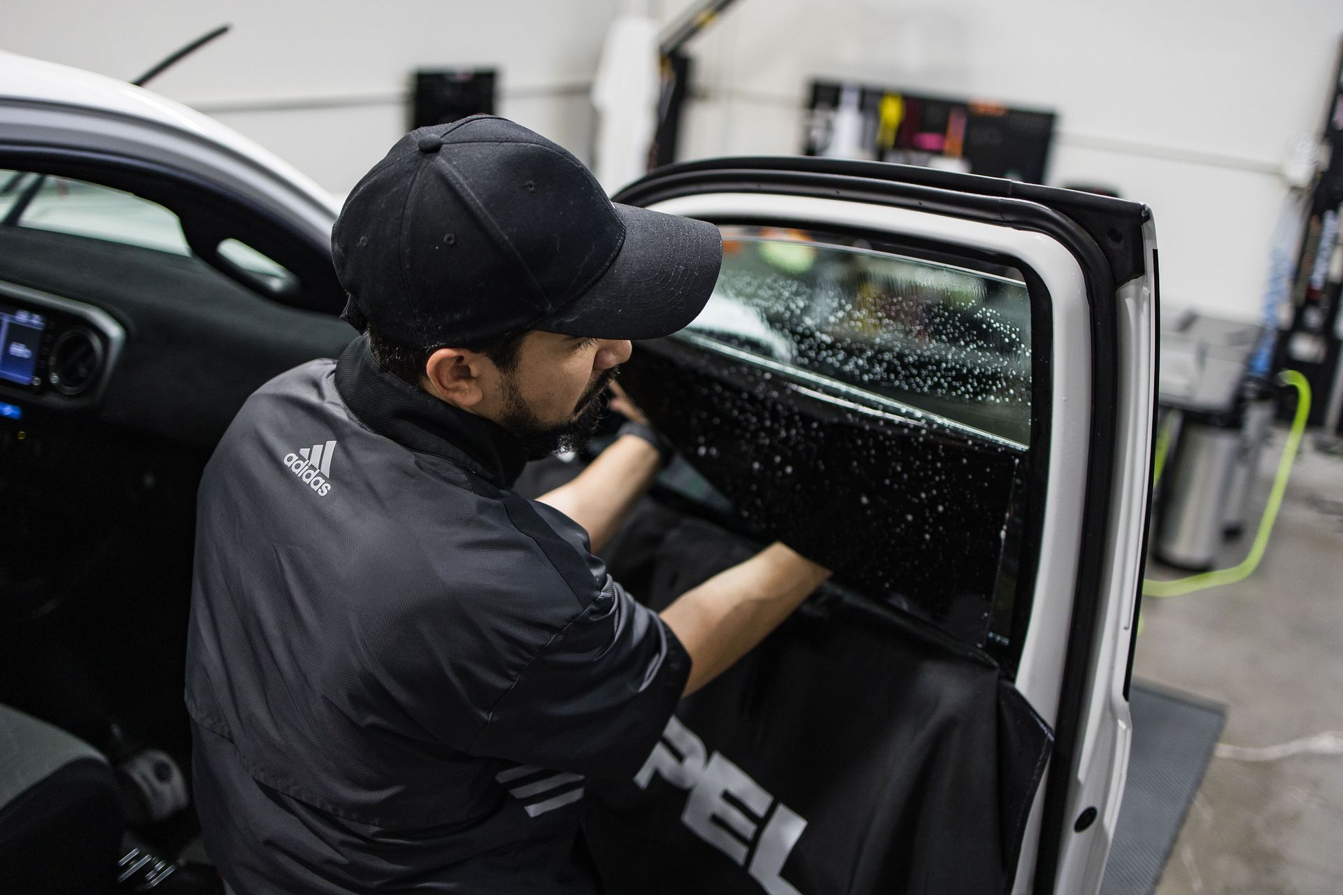 A man is installing window tinting on a car.