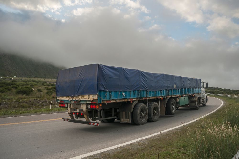 Large Truck With Blue Tarpaulin Moves on a Mountain Path — Container, Machinery & General Freight Transport in Townsville, QLD