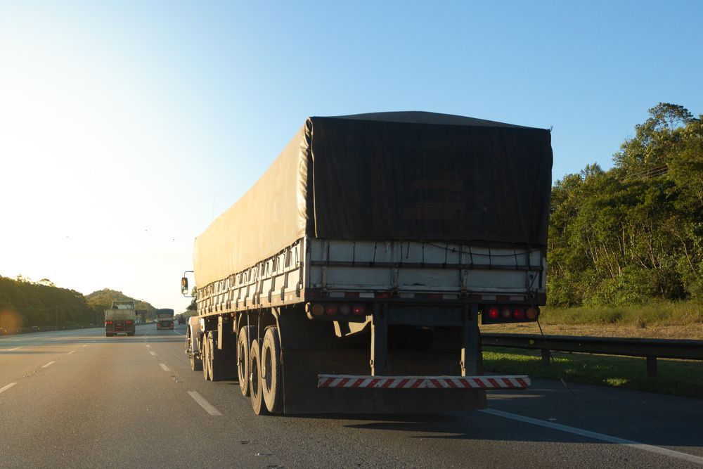 Truck Body Covered With Tarpaulin on the Road During Sunset — Container, Machinery & General Freight Transport in Rockhampton, QLD