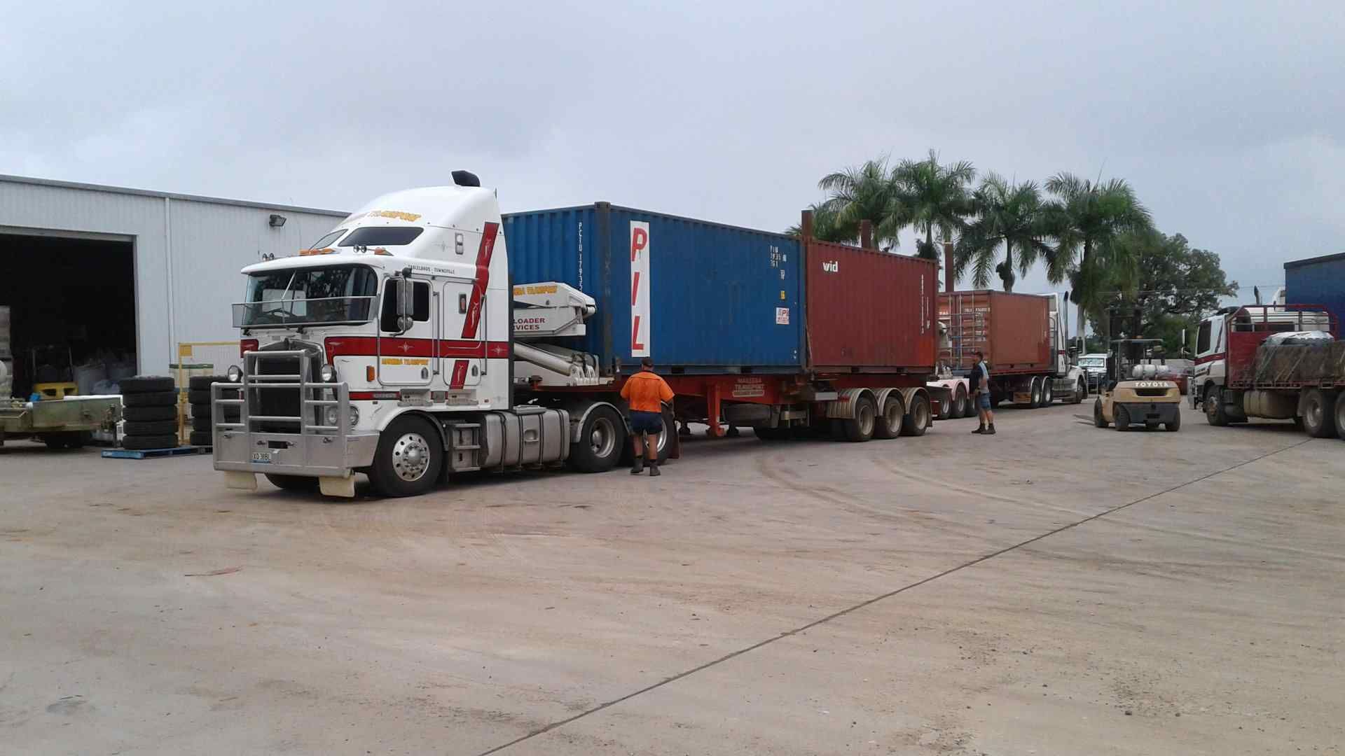 A Semi Truck With a Trailer and a Couple of Men Standing Next to It — Taking Care of Freight in Mareeba, QLD