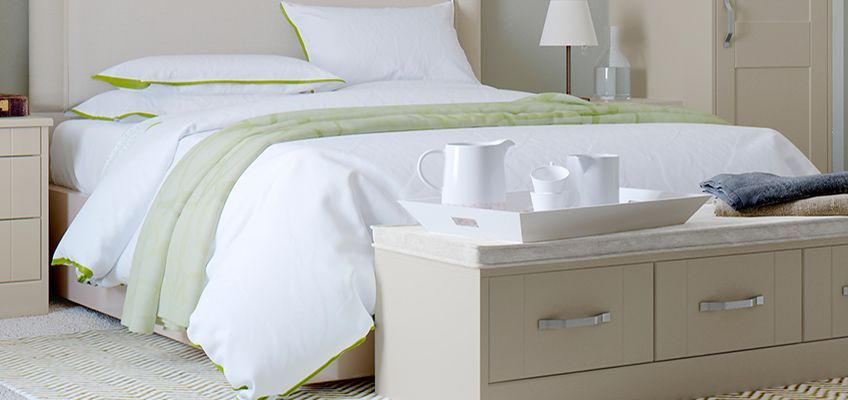 A bedroom with a bed and a bench with a tray on it.