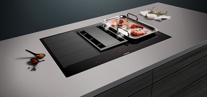 A kitchen counter with a stove top oven and a tray of food on it.
