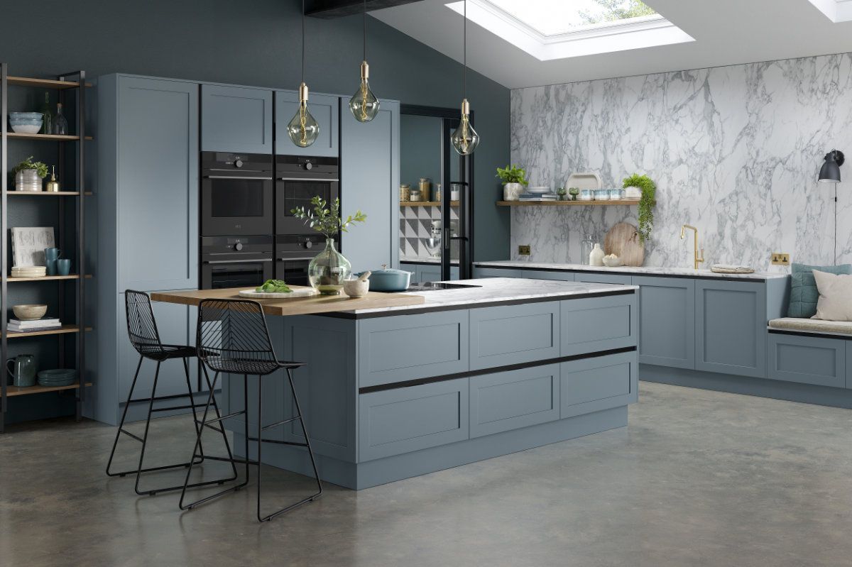 A kitchen with blue cabinets , a large island , a table and chairs.